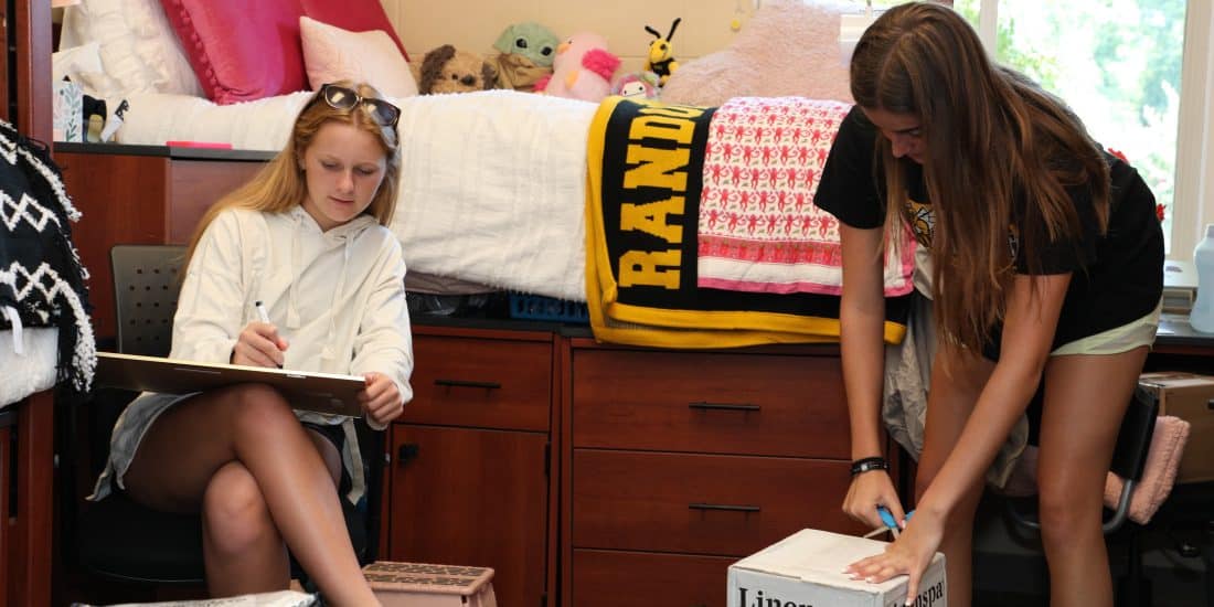 Two students unpacking in a dorm room