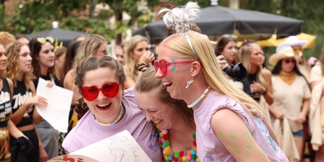 female students with red glasses laughing and hugging